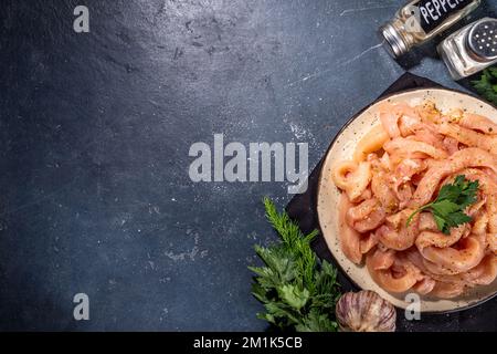 Dieta di cottura sfondo bianco di carne di pollame. Strisce di pollo fresche a fette crude per la cottura, con spezie, erbe aromatiche, su uno sfondo di cemento nero vista dall'alto c Foto Stock