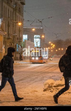 Mosca, Russia - 7 dicembre 2022: Persone che attraversano la strada vicino al tram. Il tram attraversa la città innevata d'inverno Foto Stock