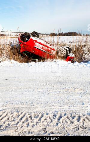 Guida invernale nel Regno Unito Un'auto ribaltata su una strada rurale coperta di neve nel Derbyshire, Emgland, Regno Unito Foto Stock