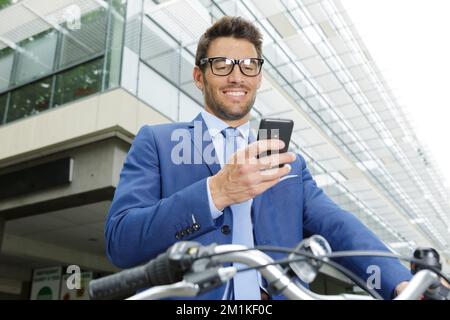 uomo d'affari in bicicletta che guarda lo smartphone Foto Stock