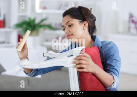 donna falegname professionista che leviga una sedia in officina Foto Stock