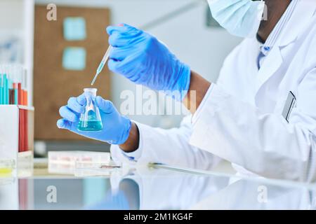 Primo piano del tecnico di laboratorio che preleva campioni liquidi con la pipetta durante le ricerche mediche Foto Stock