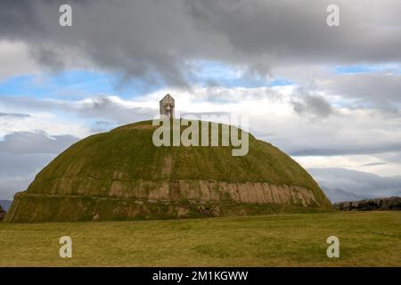 Thufa Hill come luogo di meditazione e serenità, basato sul folclore locale. Coperto da erba verde. Cielo nuvoloso piovoso. Grandi, porto di Reykjavik, Icel Foto Stock