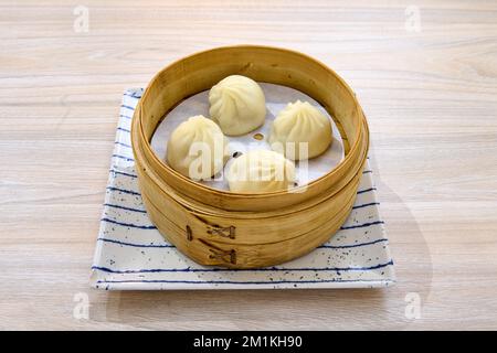 Un primo piano di deliziose focaccine cinesi al vapore di xiaolongbao su un cestino di vapore di bambù di xiaolong Foto Stock