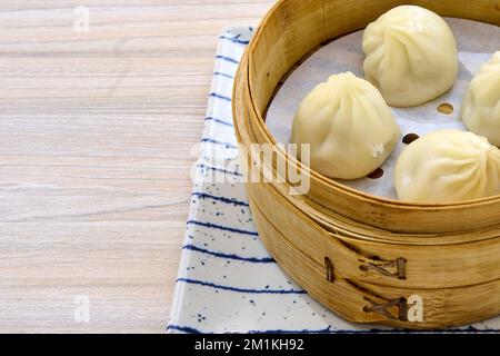 Un primo piano di deliziose focaccine cinesi al vapore di xiaolongbao su un cestino di vapore di bambù di xiaolong Foto Stock