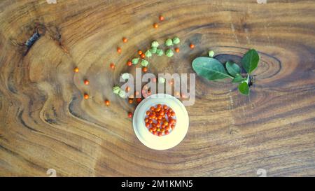 Molti ashwagandha Berry su sfondo di legno. Pianta di Withania somnifera. Frutti di bosco con foglie di ashwagandha, erbe di ginseng indiano, uva spina velenosa Foto Stock