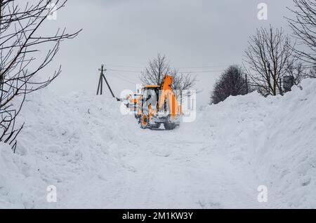 Il trattore giallo rimuove la neve all'esterno Foto Stock