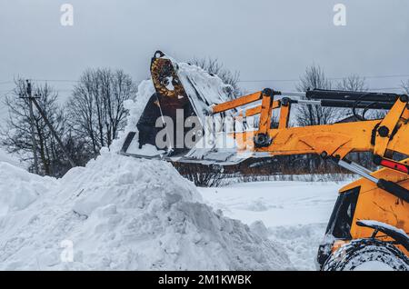 Il trattore giallo rimuove la neve all'esterno Foto Stock