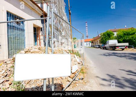 Banner informativo, lavagna metallica bianca si trova di fronte al cantiere, edificio residenziale recintato in costruzione. Foto Stock