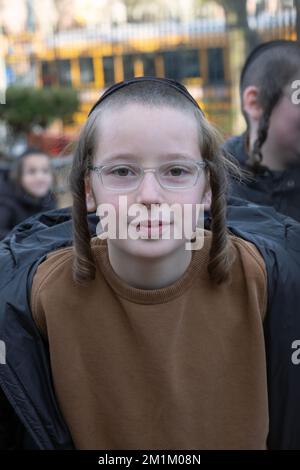 Un giovane studente di yeshiva con lunghe pose di peyot riccio per una foto di testa e spalle a Brooklyn, New York. Foto Stock