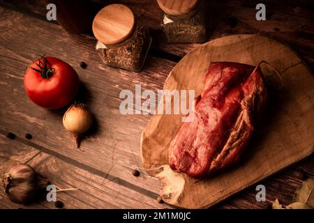 Una vista dall'alto di carne fresca e gustosa su un tavolo di legno con aggiunta di erbe fresche e spezie aromatiche Foto Stock