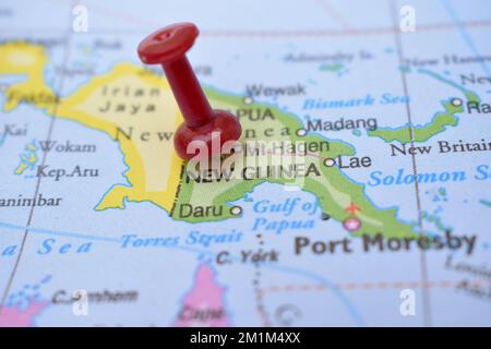 Puntino rosso che indica la posizione della Nuova Guinea primo piano della mappa mondiale Guarda la fotografia d'archivio Foto Stock