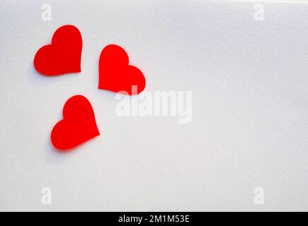 Tre cuori decorativi rossi su uno sfondo bianco scintillante con spazio copia. Tessera di San Valentino. Foto Stock