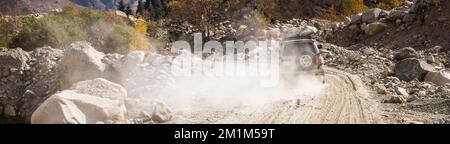 L'auto SUV bianca sale su una strada polverosa in montagna, banner ratio Foto Stock