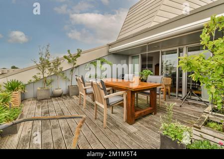 un'area soggiorno all'aperto con terrazze in legno, piante e pentole in vaso sul tavolo di fronte alla casa Foto Stock