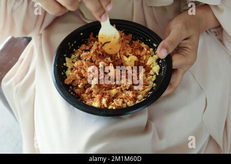 donne che mangiano pollo al curry e riso in un pacchetto di plastica da togliere Foto Stock