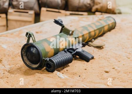 Militare, Tiro RPG anticarro lanciatore granata giacente sulla sabbia. Trofeo di guerra. Forniture militari di armi pesanti Foto Stock