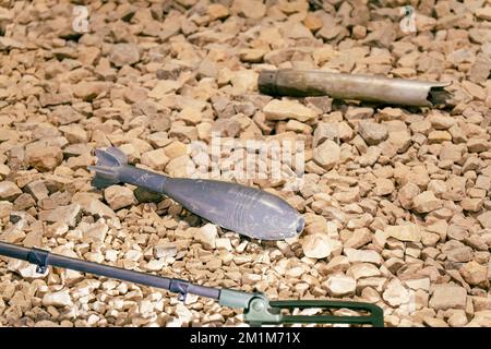 Una miniera di mortaio non esplosa che giace sulle rocce. Eliminazione di conchiglie inesplose dopo una battaglia in guerra. rilevatore di miniera Foto Stock