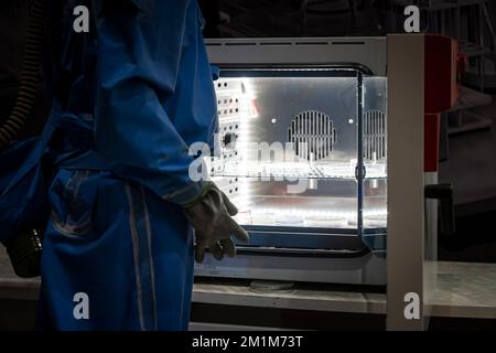 Assistente di laboratorio durante il lavoro. Concetto - l'uomo lavora in un laboratorio moderno. Chemist lavora in tuta di protezione chimica. Creazione e studio di dangero Foto Stock