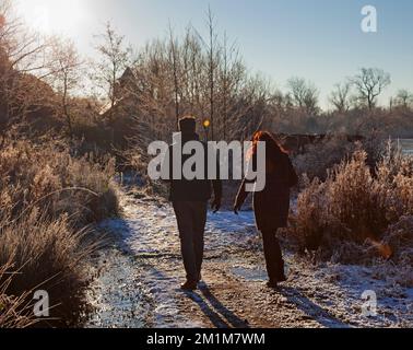 Edimburgo, Scozia, Regno Unito. 13th dicembre 2022. I residenti si sono svegliati al congelamento meno 7 gradi centigradi nella capitale scozzese, brina pesante ieri e oggi facendo per condizioni molto ghiacciate. Nella foto: Una giovane coppia cammina intorno al lago Duddingston congelato. Credit: ArchWhite/alamy live news Foto Stock