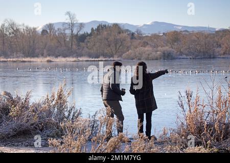 Edimburgo, Scozia, Regno Unito. 13th dicembre 2022. I residenti si sono svegliati al congelamento meno 7 gradi centigradi nella capitale scozzese, brina pesante ieri e oggi facendo per condizioni molto ghiacciate. Nella foto: Una giovane coppia cammina intorno al lago Duddingston congelato. Credit: ArchWhite/alamy live news Foto Stock