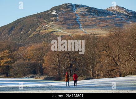 Edimburgo, Scozia, Regno Unito. 13th dicembre 2022. I residenti si sono svegliati al congelamento meno 7 gradi centigradi nella capitale scozzese, brina pesante ieri e oggi facendo per condizioni molto ghiacciate. Due maschi più grandi passeggiando attraverso il campo da golf di Duddingston, altrimenti abbandonato, con il sedile Arthur's sullo sfondo. Credit: ArchWhite/alamy live news Foto Stock