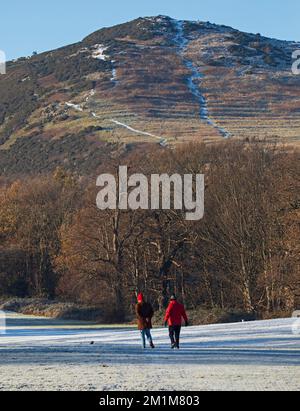 Edimburgo, Scozia, Regno Unito. 13th dicembre 2022. I residenti si sono svegliati al congelamento meno 7 gradi centigradi nella capitale scozzese, brina pesante ieri e oggi facendo per condizioni molto ghiacciate. Due maschi più grandi passeggiando attraverso il campo da golf di Duddingston, altrimenti abbandonato, con il sedile Arthur's sullo sfondo. Credit: ArchWhite/alamy live news Foto Stock