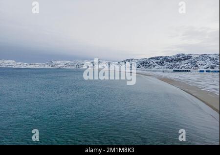 Paesaggio invernale con montagne e neve in una giornata polare, l'Oceano Artico, il Mare di Barents, l'insediamento di Teriberka, Russia. Vista dall'alto aerea Foto Stock