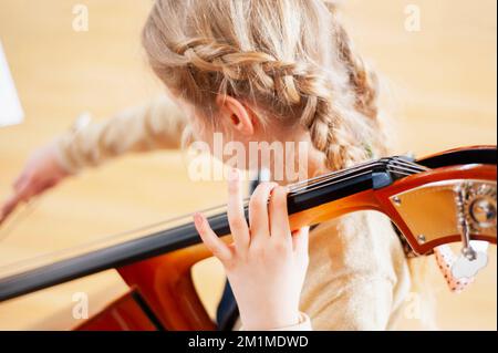 Primo piano della ragazza che gioca un violoncello messo a fuoco sulla mano superiore Foto Stock