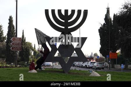 GERUSALEMME, ISRAELE - DICEMBRE 12: Un sostenitore del cosiddetto movimento anti-corruzione "bandiera nera" detiene una bandiera nera mentre attende che gli attivisti di sinistra si riuniscono per una manifestazione contro la coalizione di governo entrante che viene negoziata da Benjamin Netanyahu davanti al Parlamento israeliano. Credit: Eddie Gerald/Alamy Live News Foto Stock