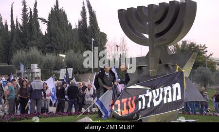 GERUSALEMME, ISRAELE - DICEMBRE 12: Gli attivisti di sinistra appendono una bandiera che recita "governo criminale” durante una manifestazione contro la coalizione di governo entrante negoziata da Benjamin Netanyahu davanti al Parlamento israeliano. Credit: Eddie Gerald/Alamy Live News Foto Stock