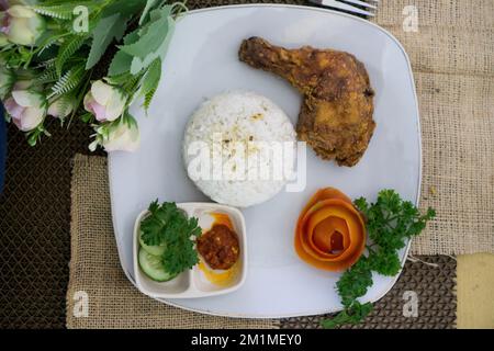 Cibo indonesiano fatto in casa, burro di pollo con riso bianco, verdure, pomodori e salsa al peperoncino Foto Stock