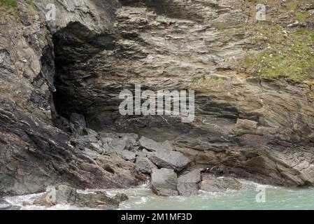 Merlin's Cave sotto il castello sull'isola di Tintagel da Tintagel Haven sul sentiero costiero sud-occidentale in Cornovaglia, Inghilterra, Regno Unito. Foto Stock