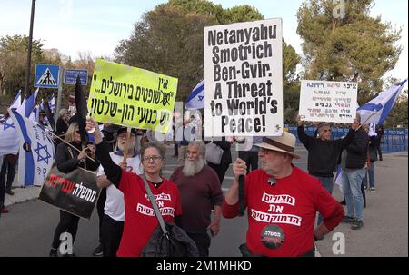 GERUSALEMME, ISRAELE - DICEMBRE 12: Gli attivisti di sinistra tengono i segni mentre prendono parte a una manifestazione contro la coalizione di governo entrante negoziata da Benjamin Netanyahu davanti al Parlamento israeliano. Credit: Eddie Gerald/Alamy Live News Foto Stock