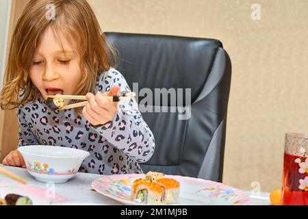 Il bambino meraviglioso è felice di mangiare sushi con salsa di soia Foto Stock