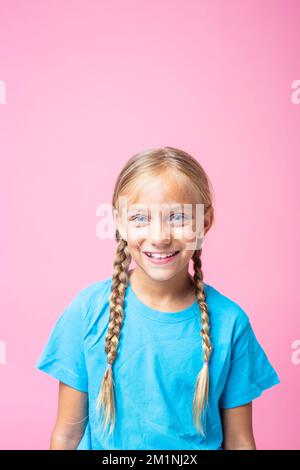 Verticale studio ritratto con sfondo rosa di una ragazza felice con trecce Foto Stock