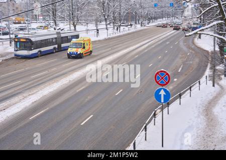Riga, Lettonia - 13 dicembre, 2022: L'auto gialla dell'ambulanza si muove lungo la strada invernale della città sfocata in azione. Foto Stock