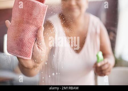 Primo piano immagine di sfondo della donna anziana pulizia vetri finestre mettere a fuoco sulla mano tenendo la salvietta, copia spazio Foto Stock
