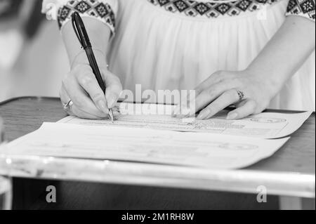 Matrimonio in un'istituzione statale, istituzione statale Ucraina per il registro delle nozze, la sposa firma il documento, foto in bianco e nero. Foto Stock