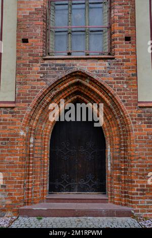 Vecchia porta gotica in legno in un edificio in mattoni Foto Stock