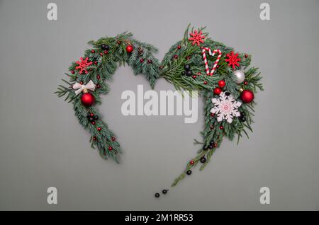 Composizione di Natale. Simbolo del cuore di pino, cipresso, rami di thuja, palle, bacche e decorazioni in legno. Natale, inverno, Capodanno c Foto Stock