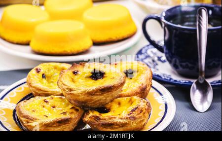 Dessert tradizionale portoghese di pastello de nata, e bree de lis sullo sfondo, servito con caffè, dolce tipico fatto con uova Foto Stock