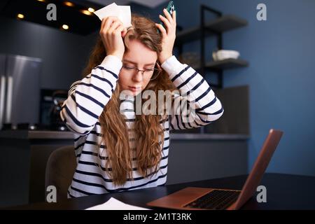 Donna scioccata calcola le spese sulle fatture, turbata circa i prezzi aumentati delle utenze. Paghe, debiti, prestiti, ricevute per pagare le tasse Foto Stock