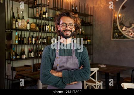 Guardando il ritratto della macchina fotografica del giovane proprietario di un piccolo commercio locale.allegro lavoratore maschio sorridente Foto Stock