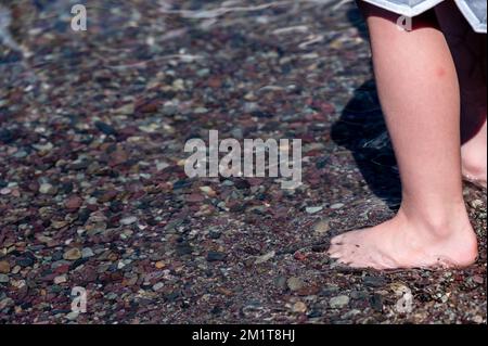 Punte a piedi nudi nelle rocce multicolore di Rainbow nel torrente delle valanghe che conducono verso il lago McDonald al Glacier National Park, Montana, USA Foto Stock