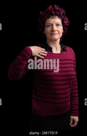 Foto studio di una donna che indossa una camicia nera un maglione a righe nere e rosse e gioielli Foto Stock