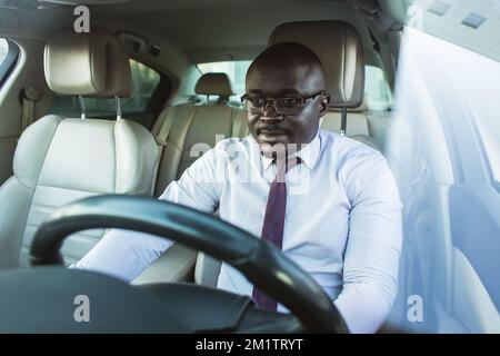 Ritratto di un bell'uomo d'affari afroamericano di successo alla guida della sua auto Foto Stock