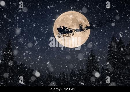 Babbo Natale in una slitta con renne vola sulla terra nel cielo stellato notturno con una grande luna incredibile con neve caduta. Magia e felice New Yea Foto Stock