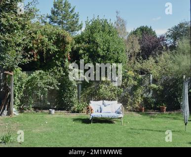 Finestra con vista sul giardino illuminato dal sole e mobili in Inghilterra. Foto Stock