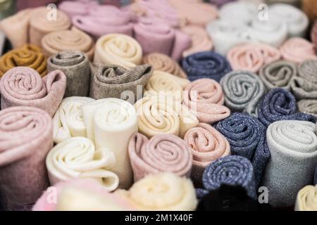 Tessuti a maglia colorati di colore pastello arrotolati in rotoli, vista dall'alto, messa a fuoco selettiva Foto Stock